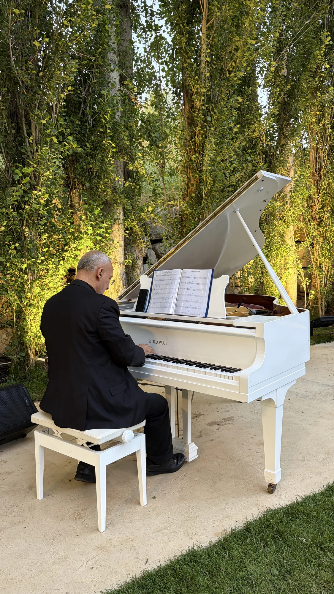 Pierre Basbous playing a white Kawai grand piano outdoors at Le Clos de Faqra