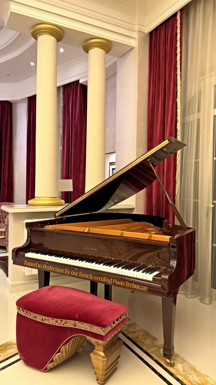 A grand piano tuned in a salon with columns and red curtains